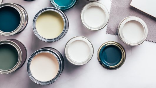 Tiny sample paint cans during house renovation, process of choosing paint for the walls, different green and beige colors, color charts on background, banner size